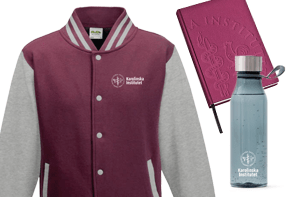 Jacket, bottle of water and notebook with Karolinska Institutets logotype