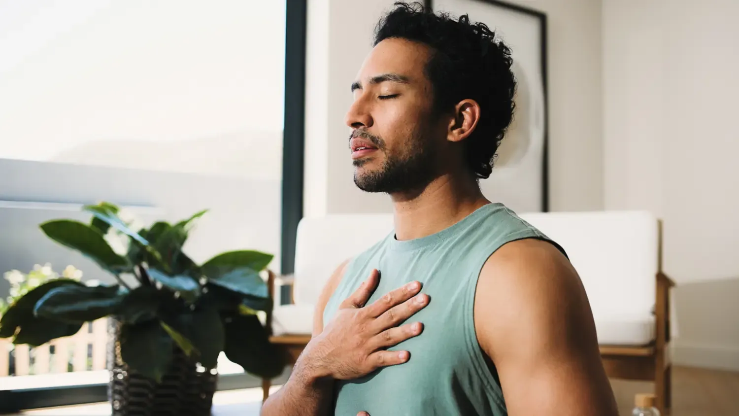 Man standing with closed eyes and hand on chest taking a breath.