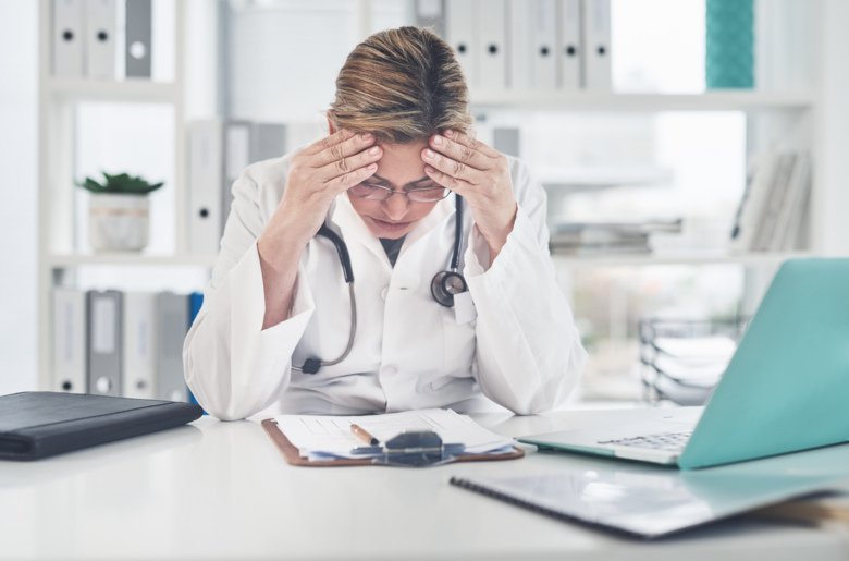 Worried, female doctor massaging her forehead.