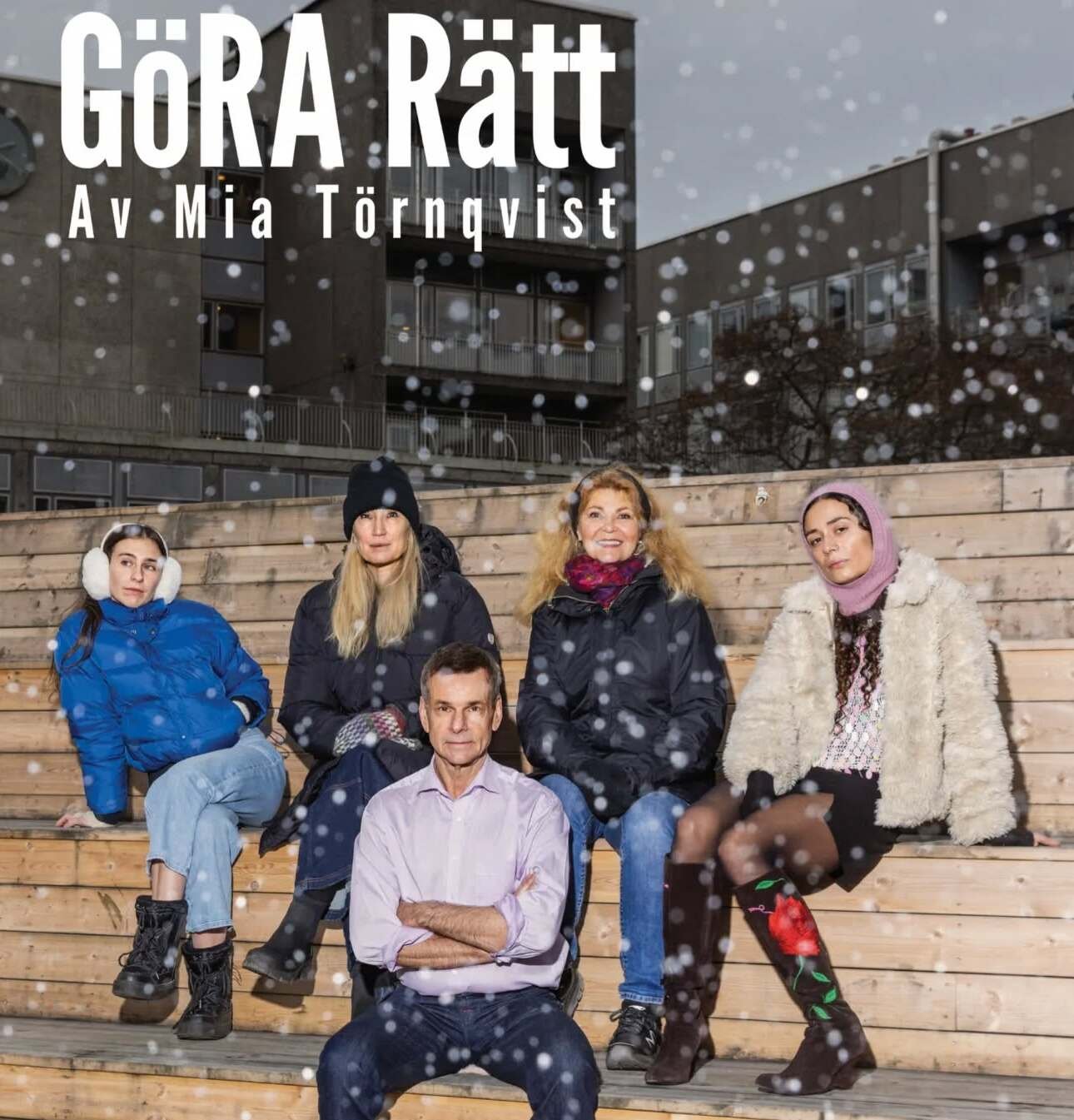 Five people sitting on a bench and it is snowing.