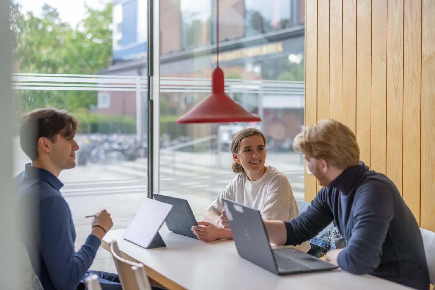 Three students studying and talking together on campus.
