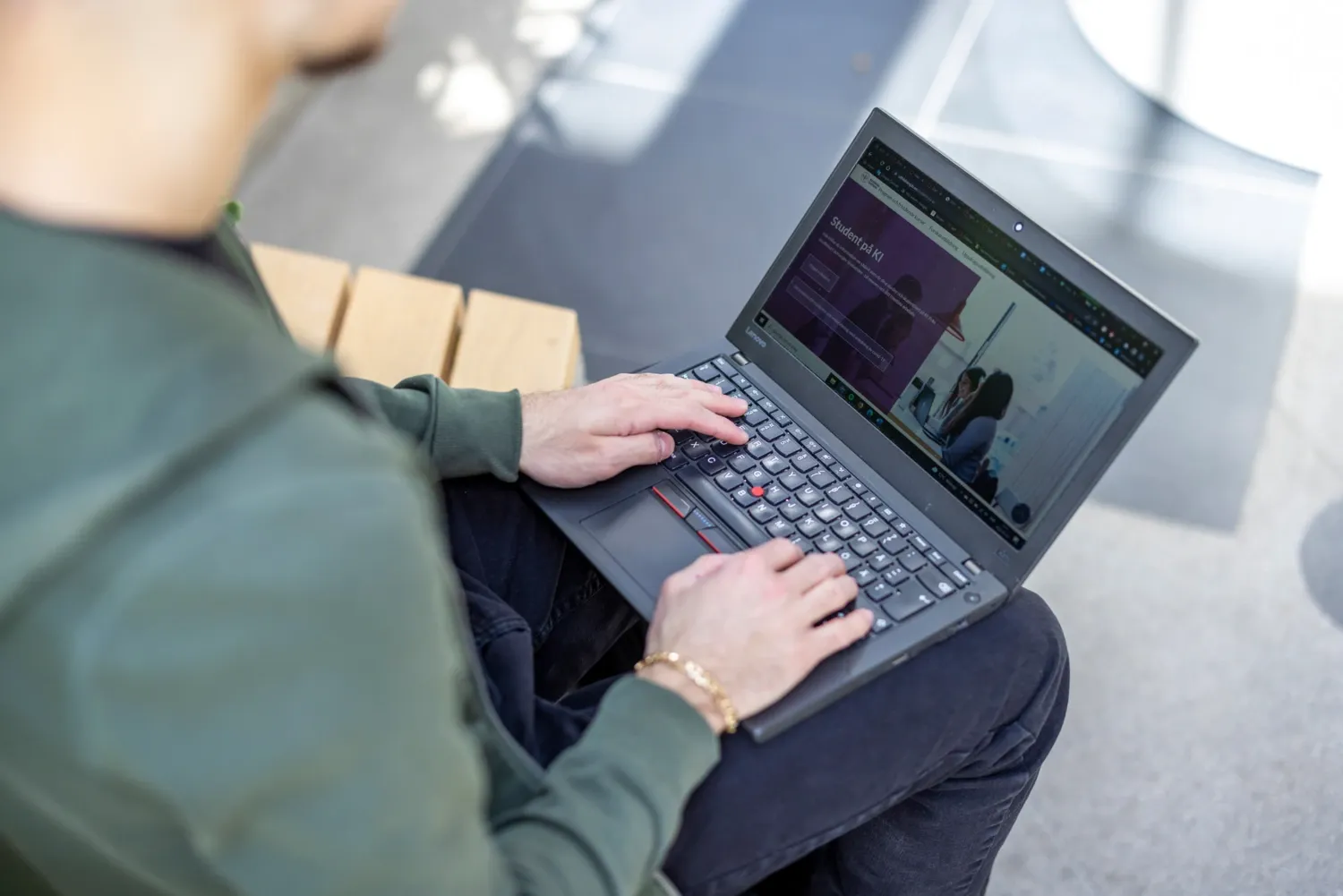 A student is sitting with his laptop in his knees.