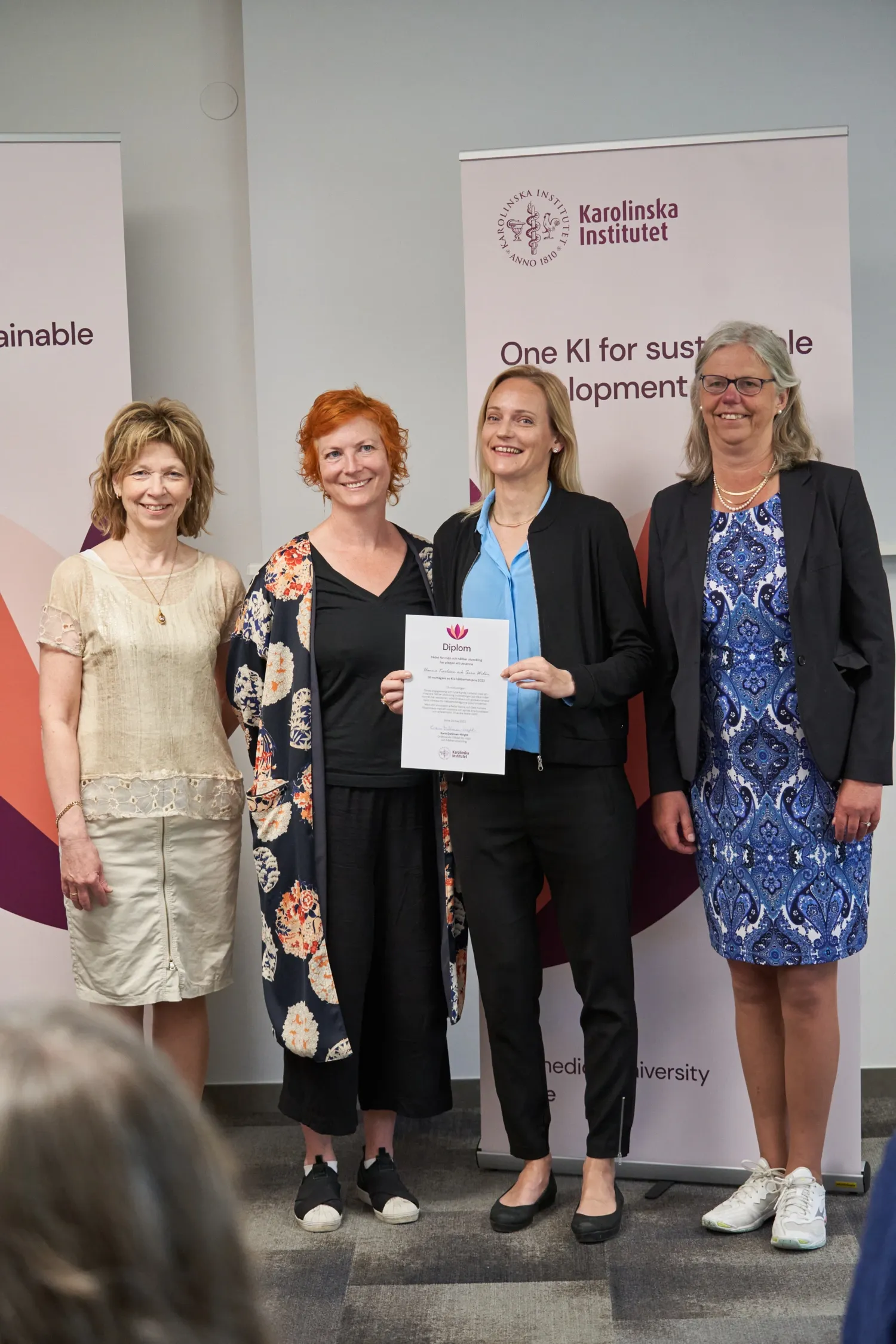 Hanna Karlsson and Sara Widén hold up their diploma, flanked by KI's president Annika Östman Wernersson and Karin Dahlman-Wright, chair of the Council for the Environment and Sustainable Development.