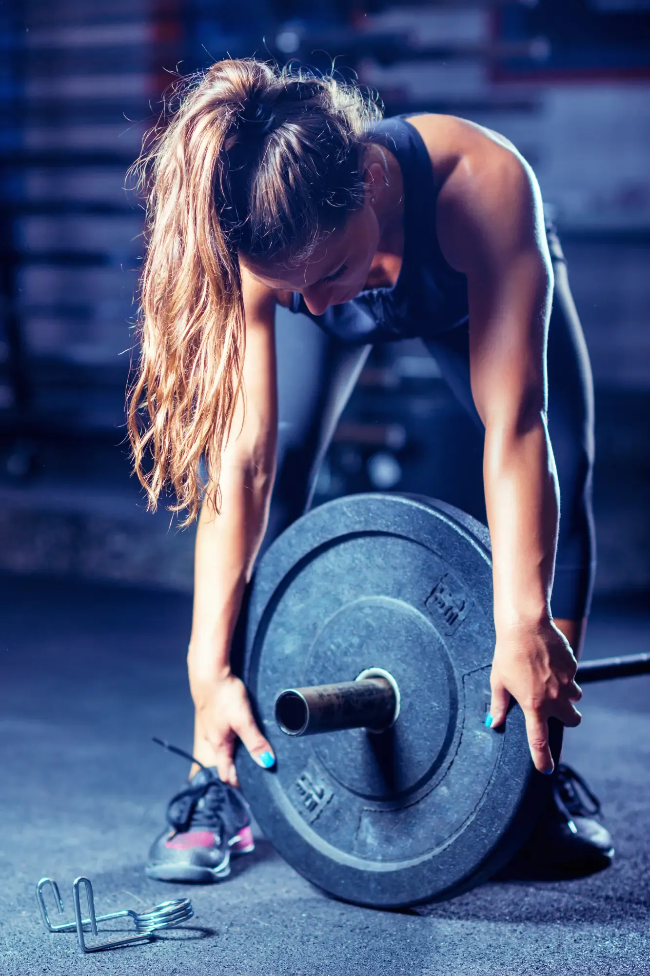 Woman putting weight plates on a barbell.