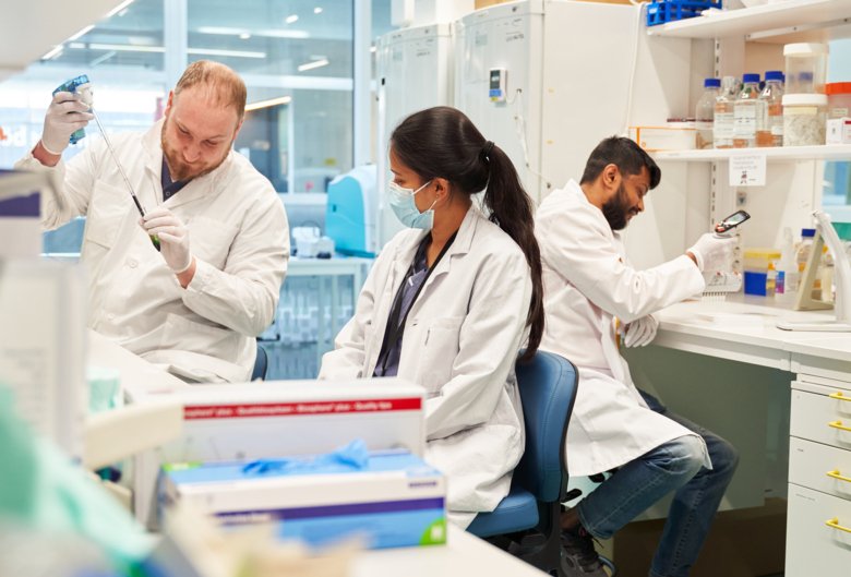 Three researchers sitting in a lab environment.