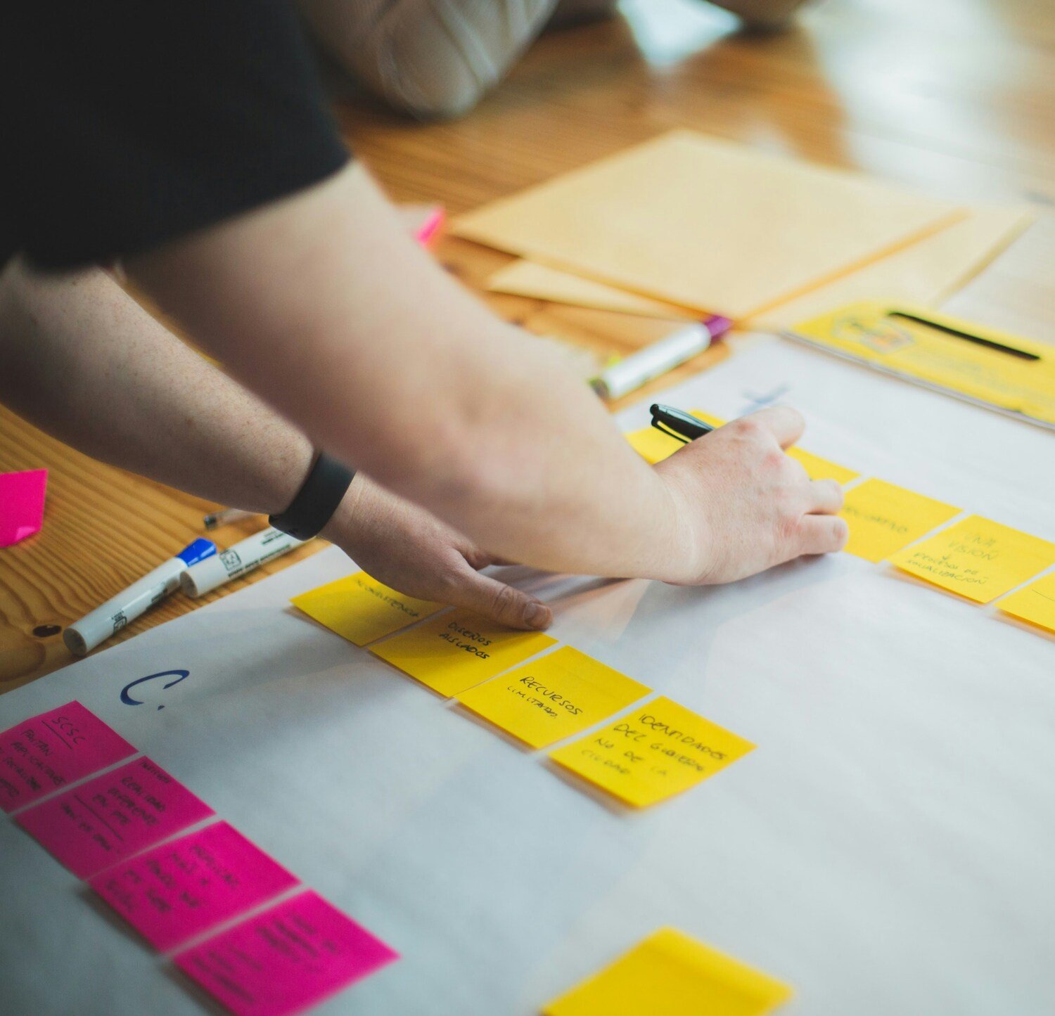 Person writing at sticky notes.