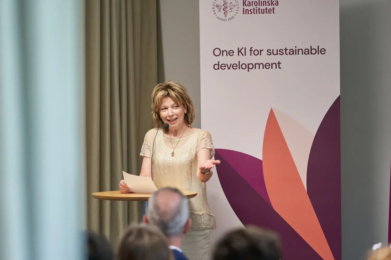 KI's president gives a speech in front of a roll-up with the text 