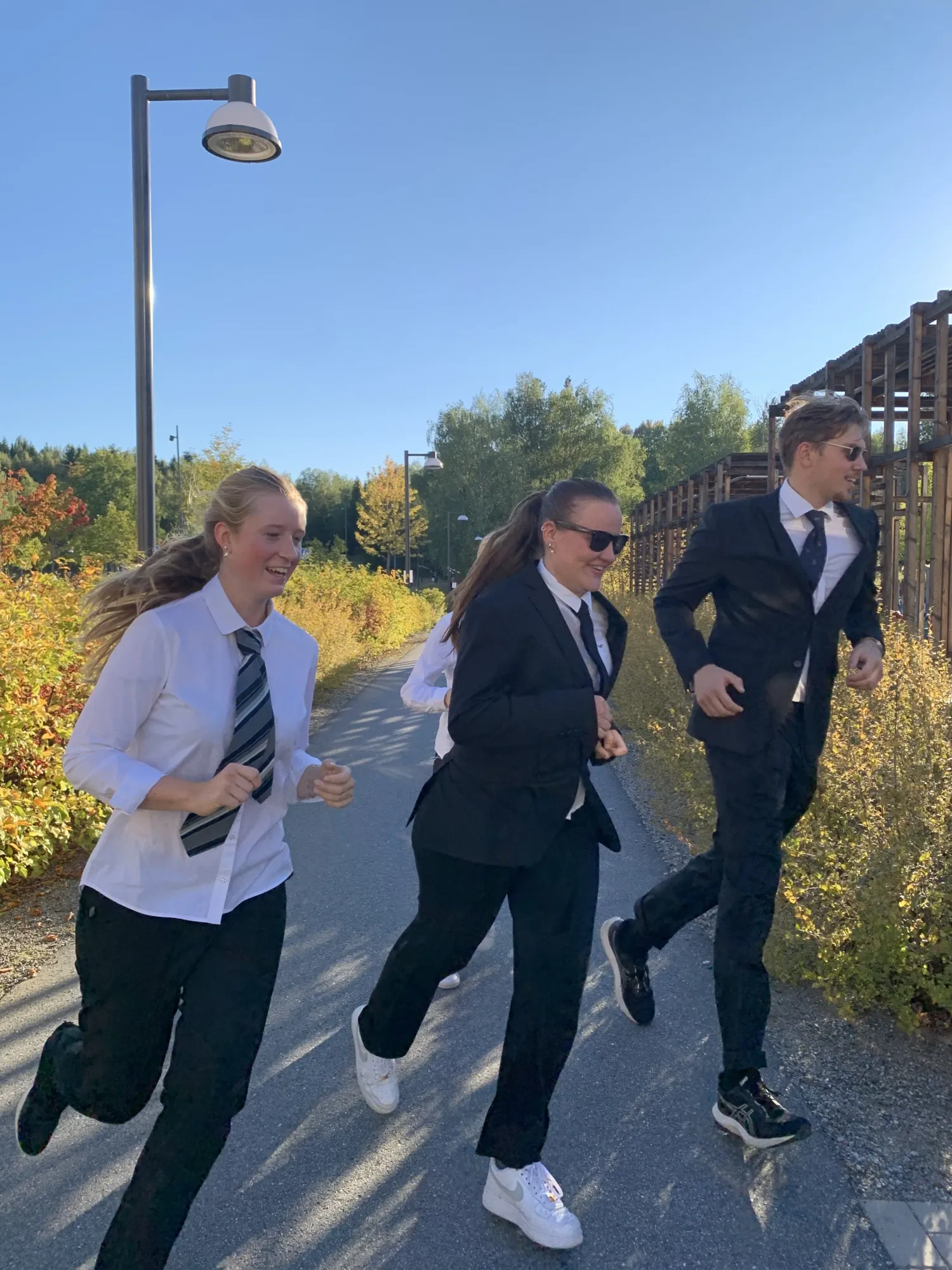 Female runners in shirt, tie and jacket take the curve in style