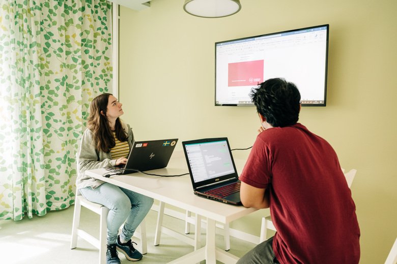 Two students in a group room in the library in Solna