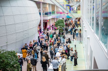 Overview image from the building Neo during the conference. People standing in an open space, chatting.