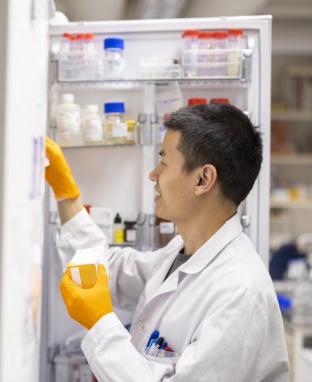 Man in lab environment getting something from a fridge.