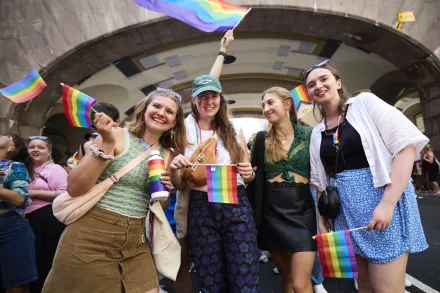 Alina Lapp, Maureen Verdier, Teresa Reindl and Katharina Schormair smiling in the street at the parade holding rainbow flags.