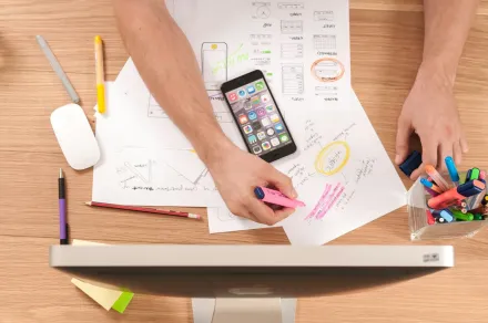 Picture taken from above on a table with paper, pens and a smartphone.